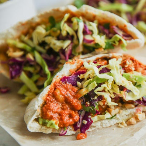 A pita sandwich filled with Indian Butter ChickPeas and garnished with cabbage slaw