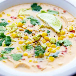 A bowl of mexican corn chowder garnished with cilantro and a lime wedge. 